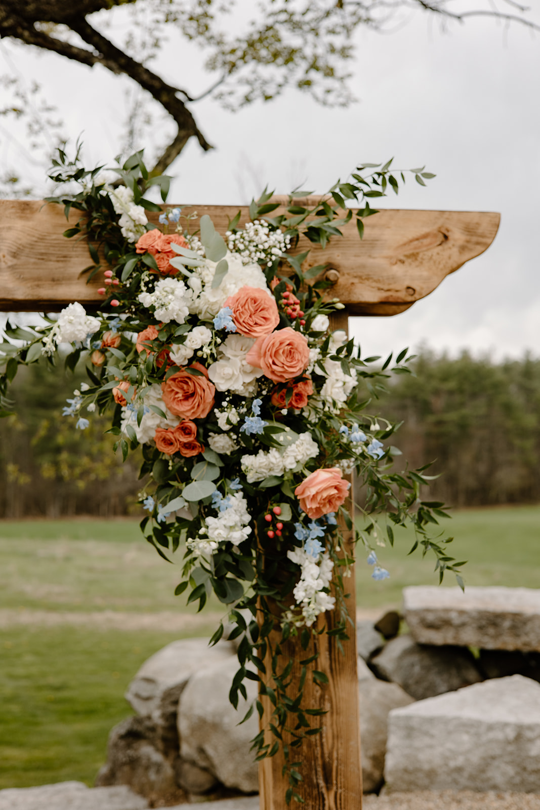 Wedding arch floral arrangement with orange and blue flowers and babies breath.
