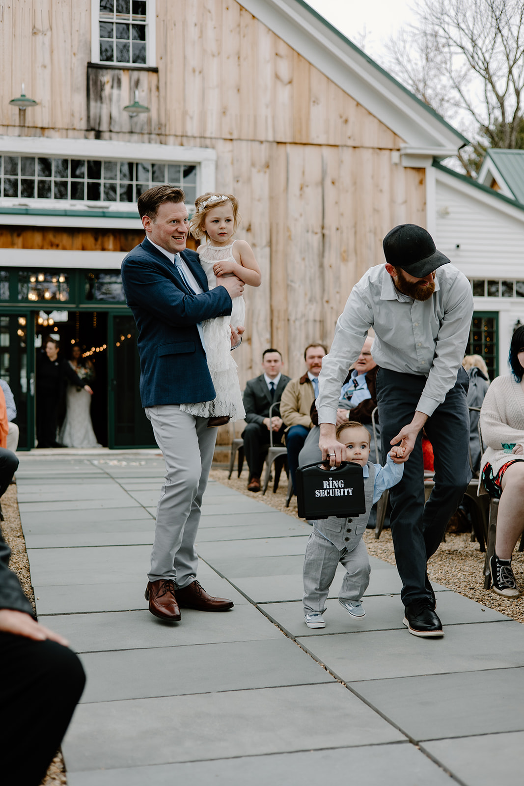 Flower girl and ring bearer being escorted down the aisle by their dads.