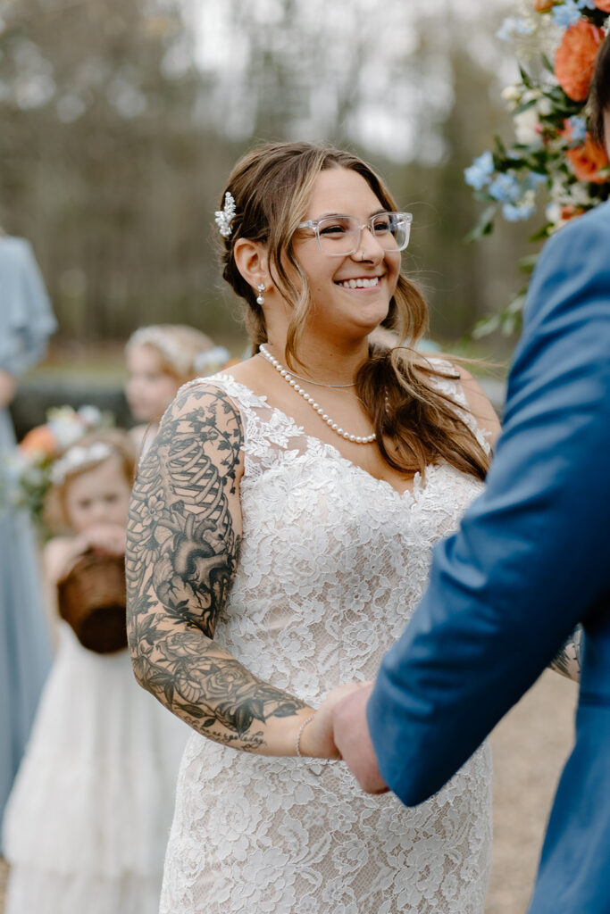 Bride holding hands with the groom during their wedding ceremony.