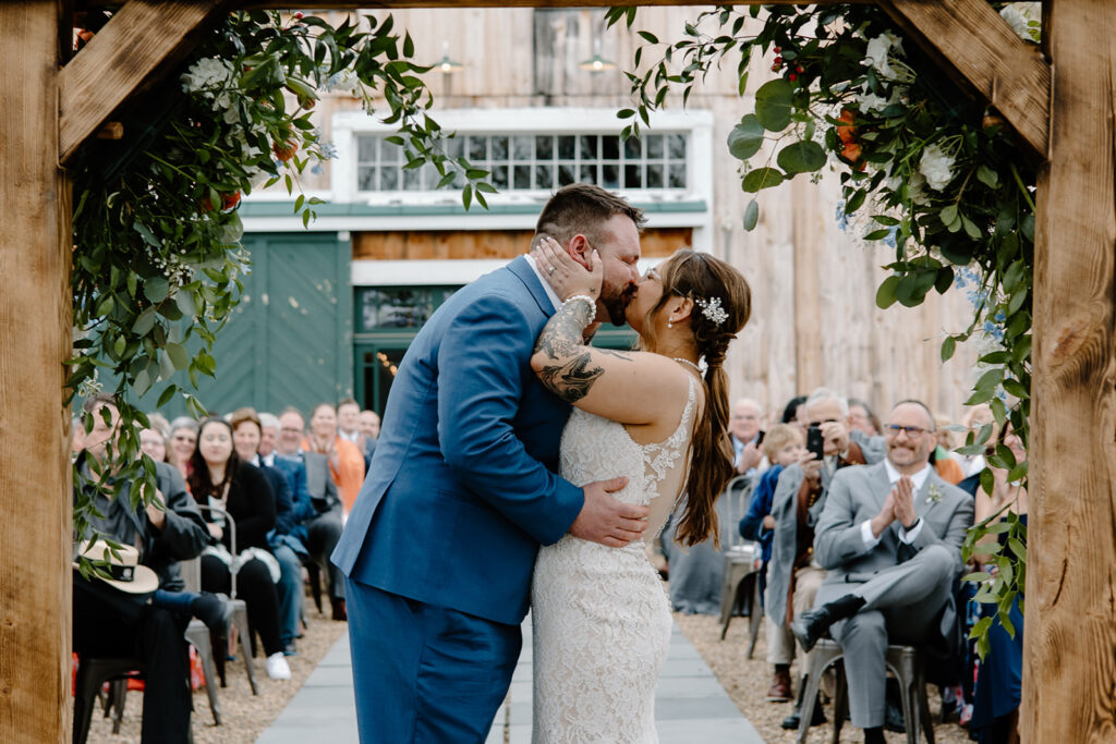 Bride and groom wedding ceremony first kiss from behind the altar.