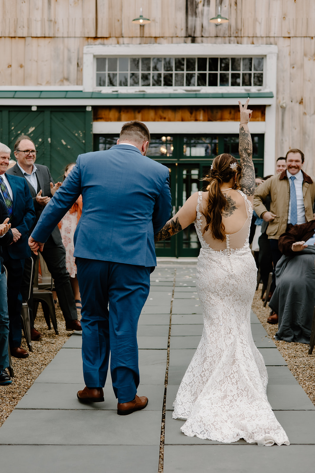 Bride holding up peace fingers as she walks down the aisle with her new husband.