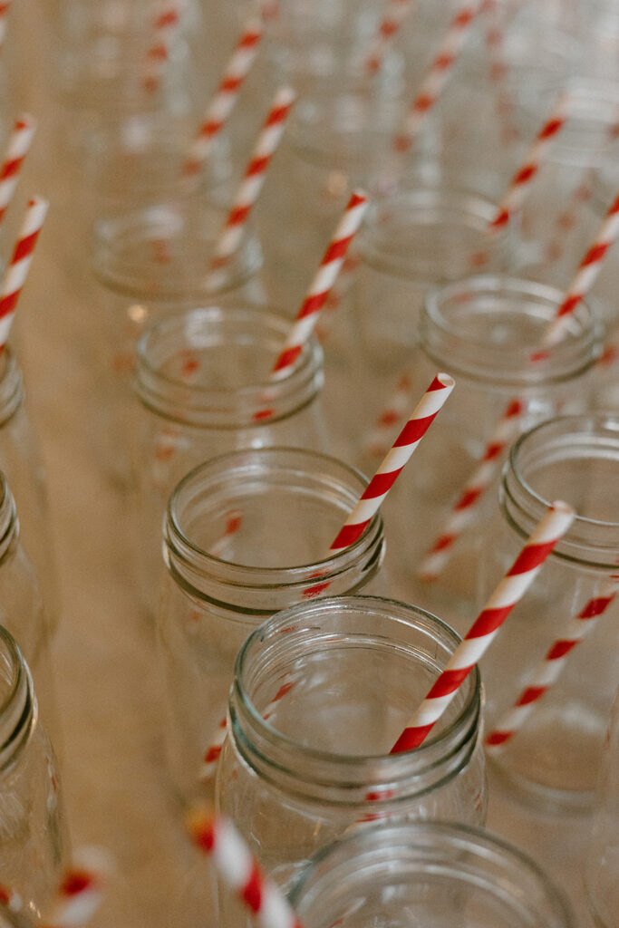 Rustic wedding mason jars and red striped straws.