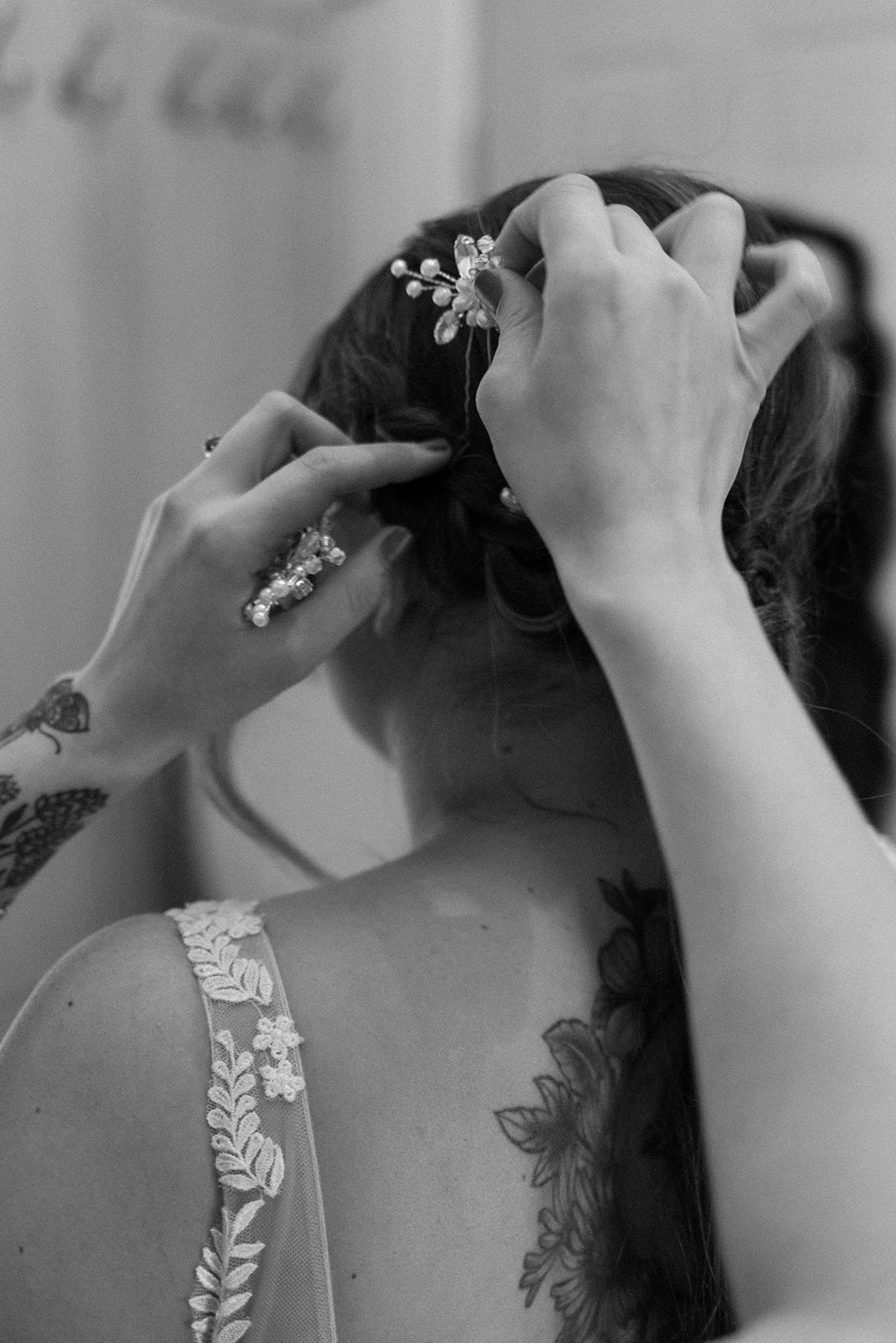Bridesmaid putting white floral hair pins in the bride's hair to complete her look.