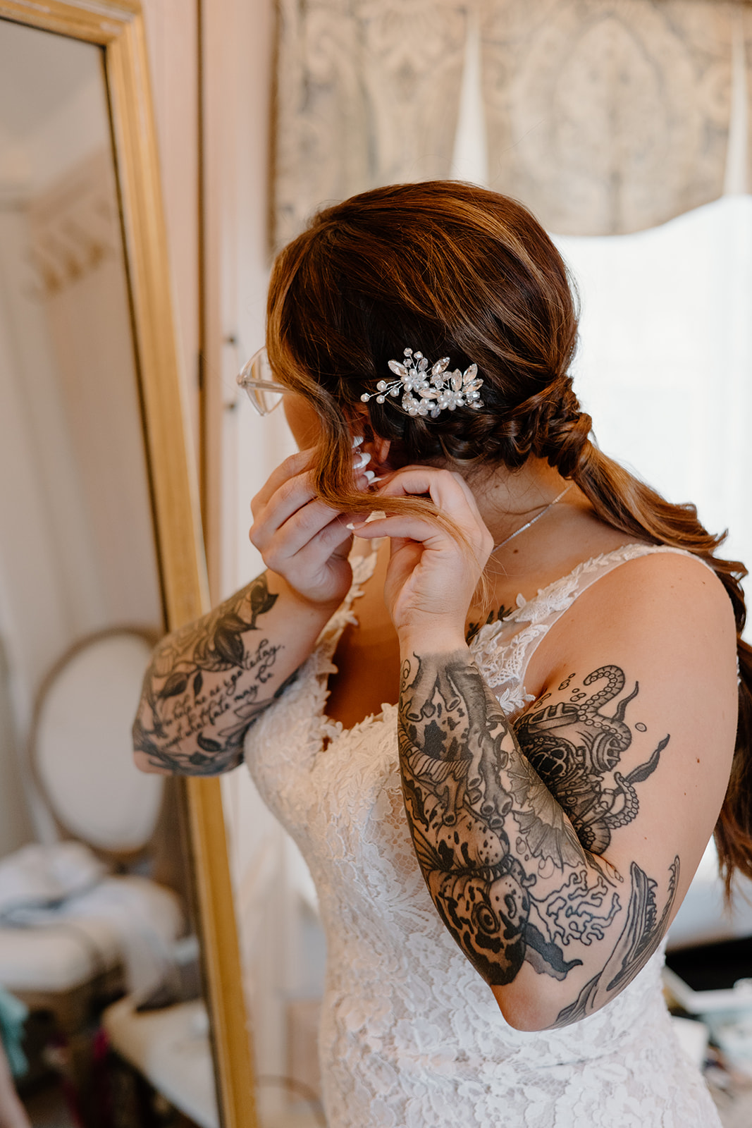Bride putting on earrings in front of a mirror.