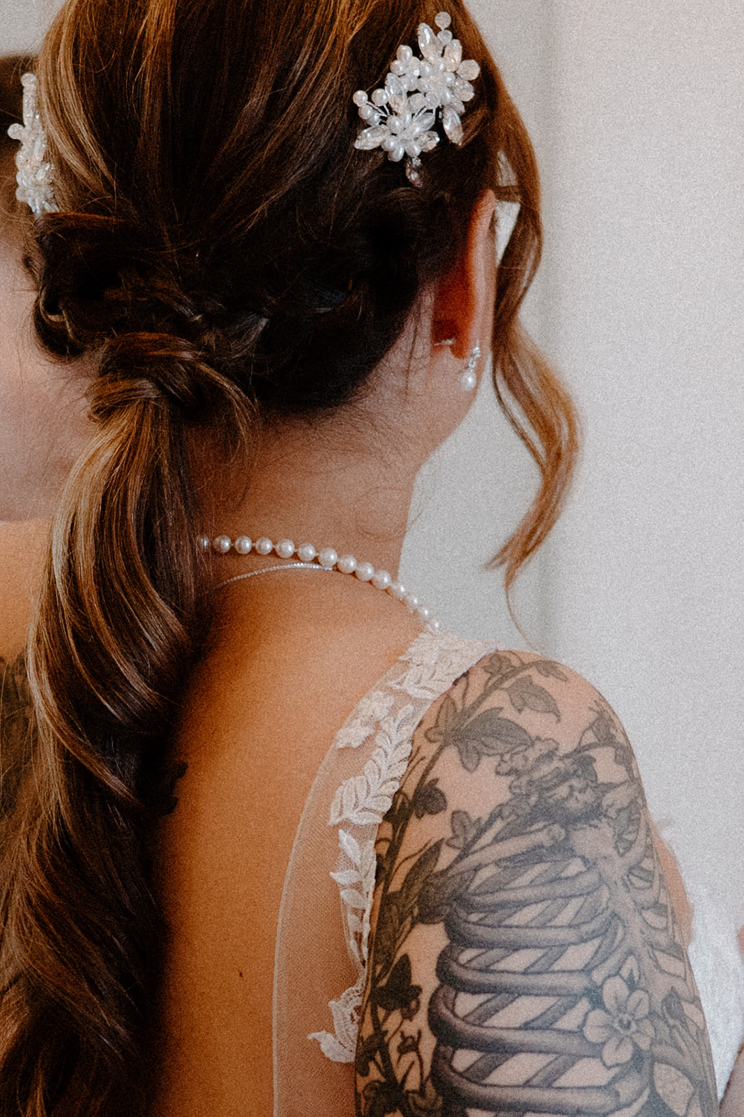 Close up detail shot of a bride with a pearl necklace and braided low-ponytail hairstyle.