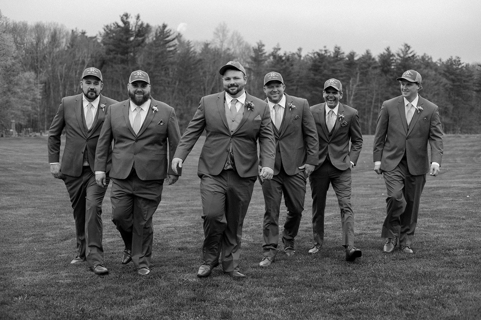 Groom and groomsmen walking and wearing trucker hats.