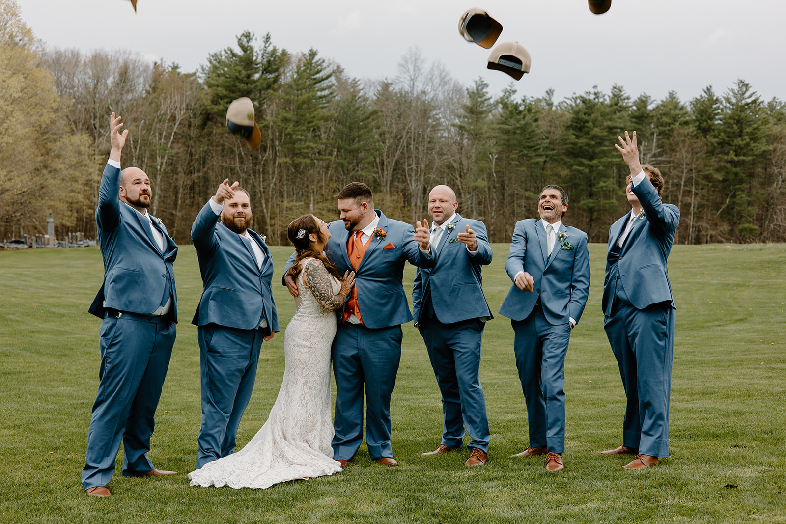Bride and groom with groomsmen throwing up trucker hats.