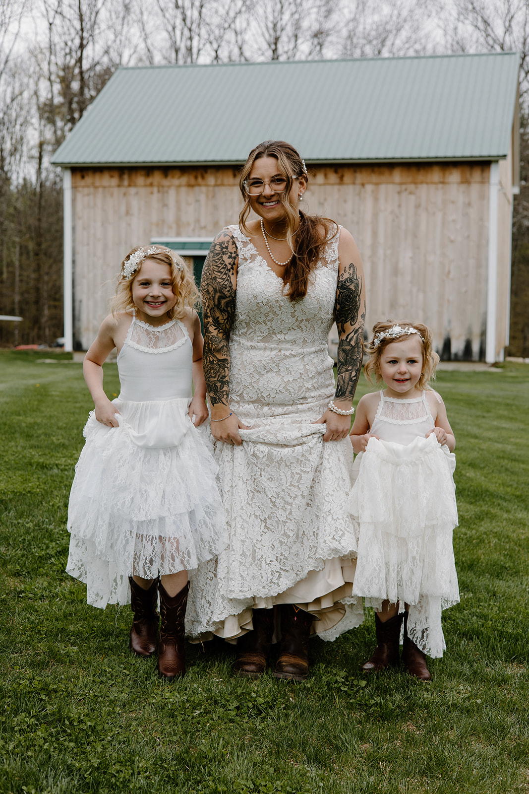 Bride and flower girls holding up their dresses to show their cowgirl boots.