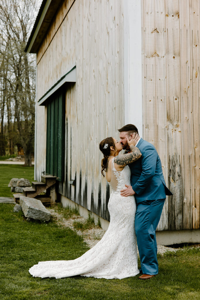 Bride and groom kissing outside of Powder Major's Barn in Madbury, New Hampshire.