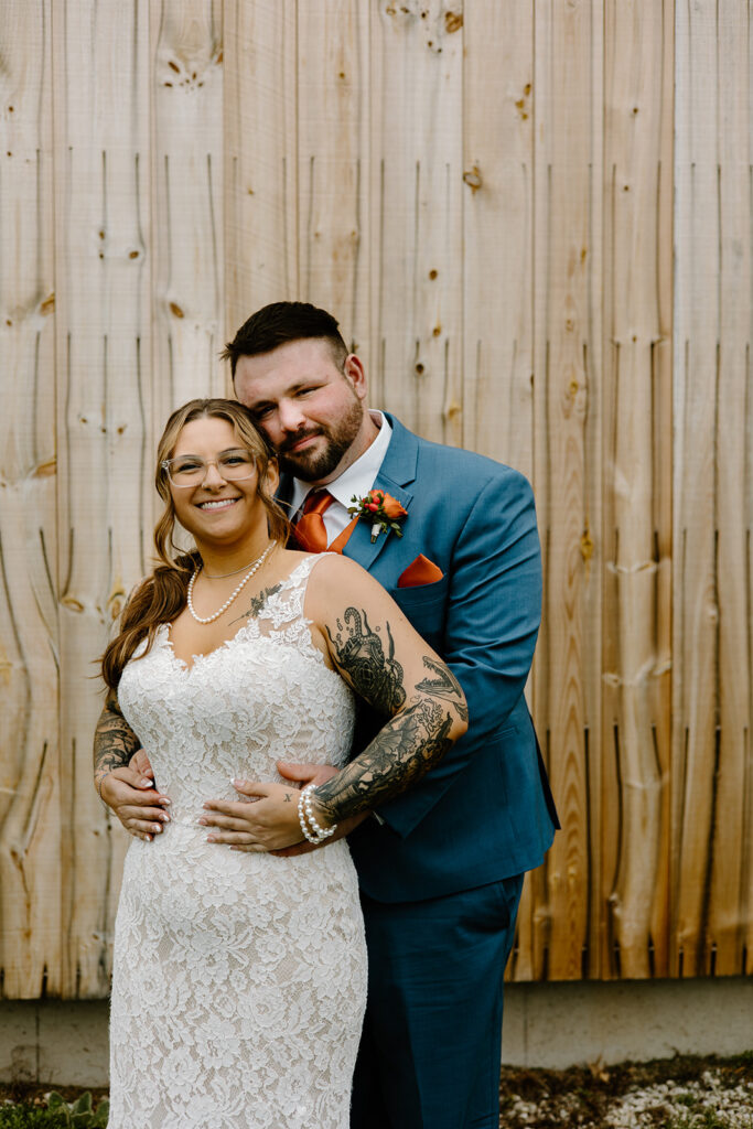 Bride and groom posing in front of a rustic barn.
