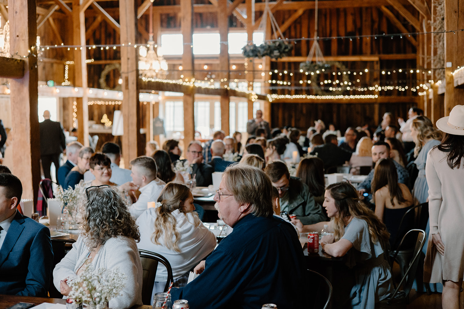 Guests listening to speeches at a rustic barn venue.