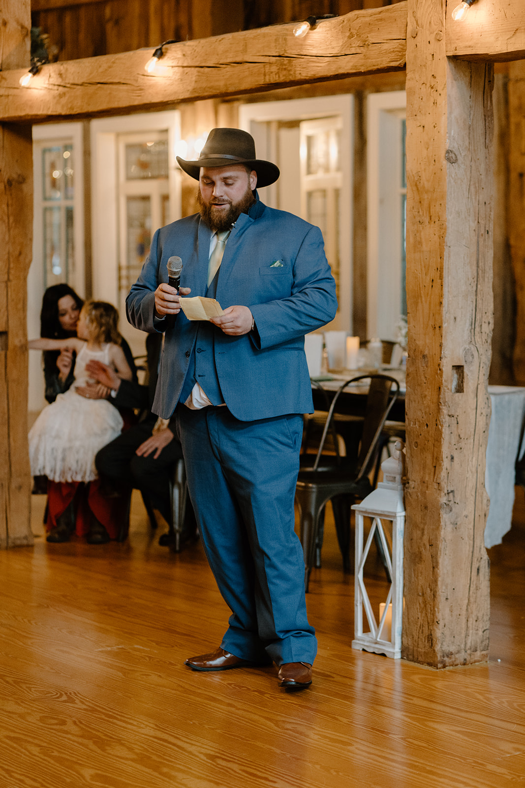 Wedding best man giving a speech during a rustic barn wedding reception.