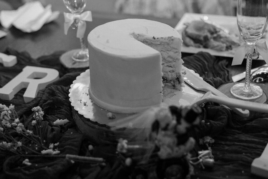 Black and white image of a wedding cake with piece cut out.