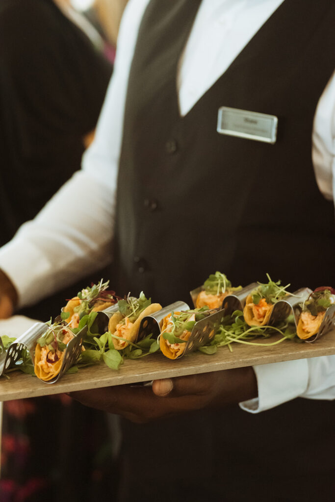 Caterer holding a tray of tacos.