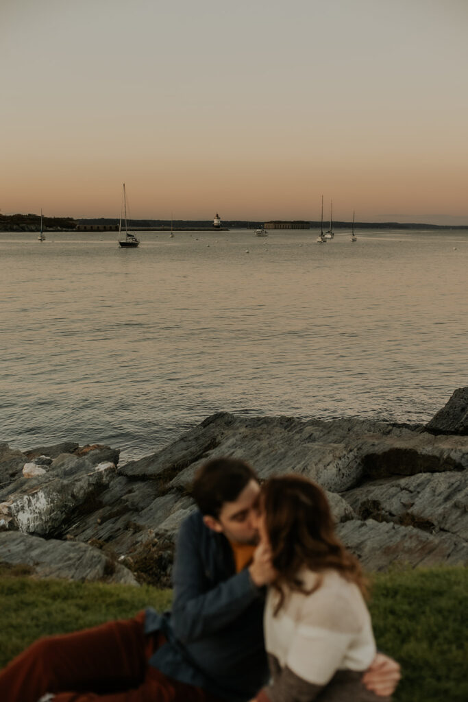 Couple kissing on the grass at Fisherman's Point in Portland Maine.