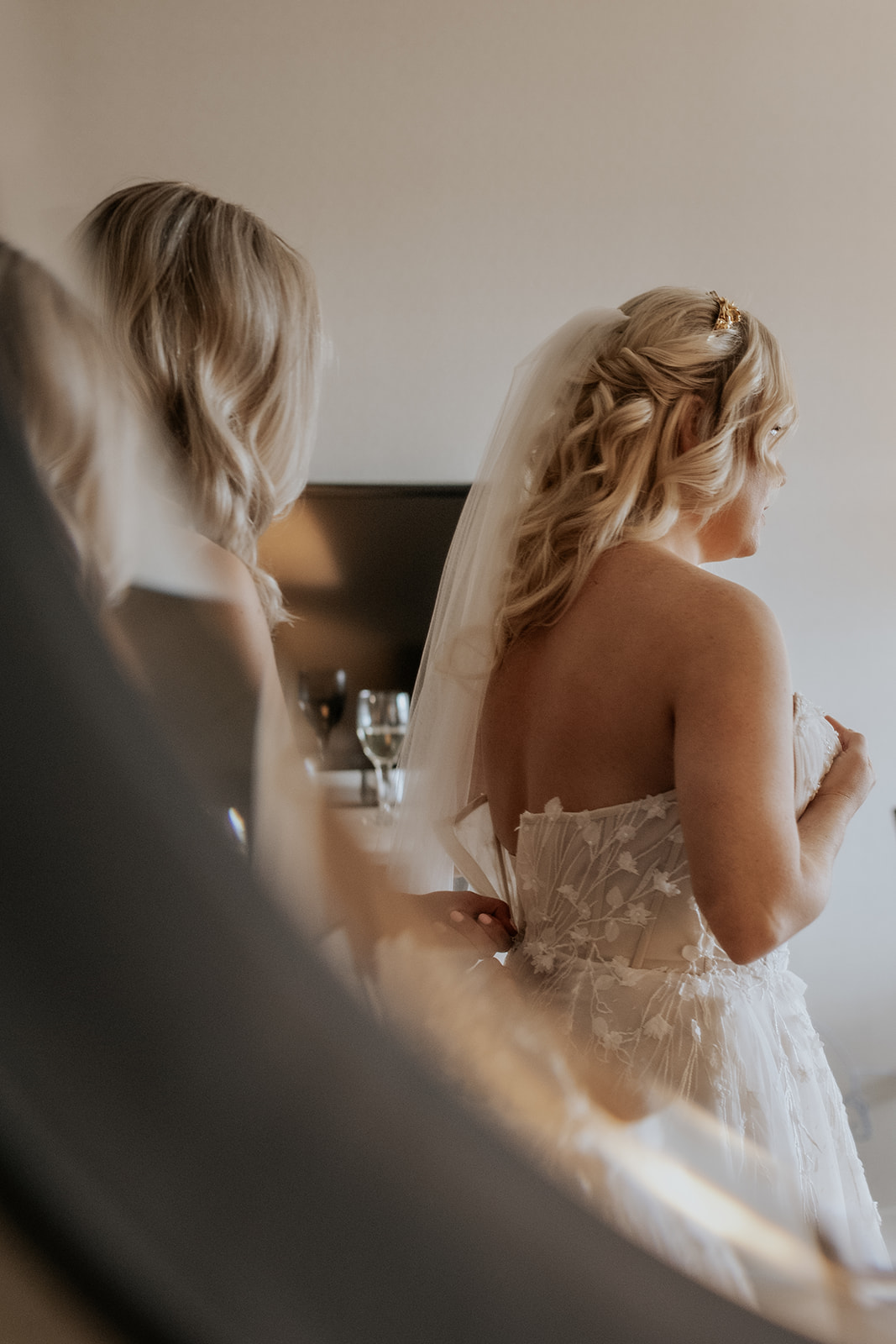 Bride getting her dress zipped up in a cozy Maine resort.