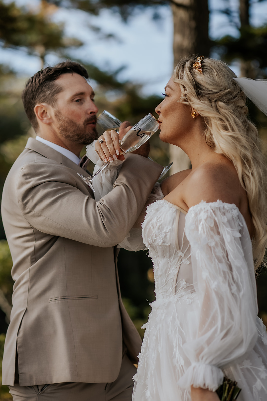 Bride and groom linking arms and drinking champagne.