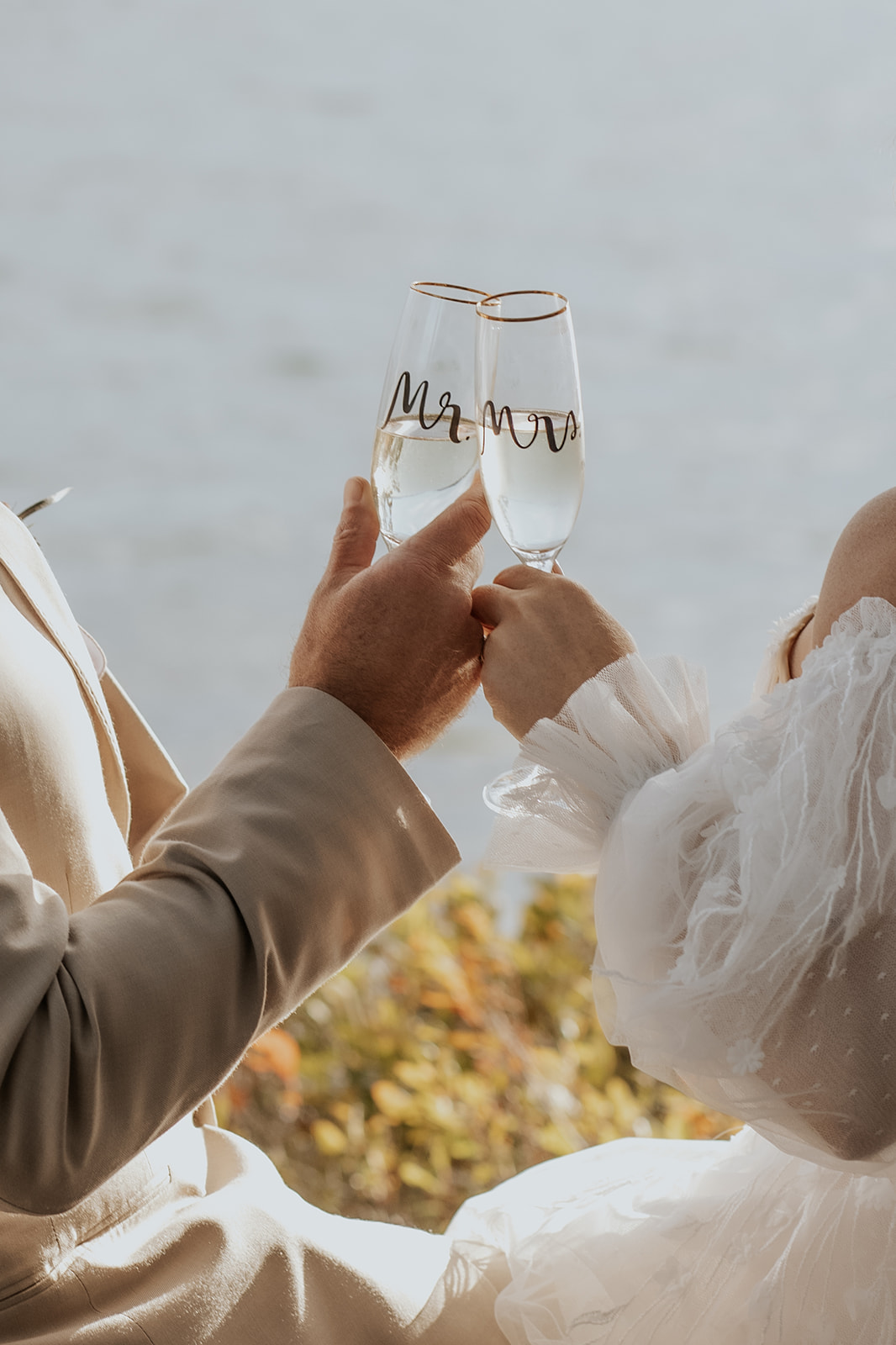 Bride and groom toast with "Mr. and Mrs." champagne glasses.