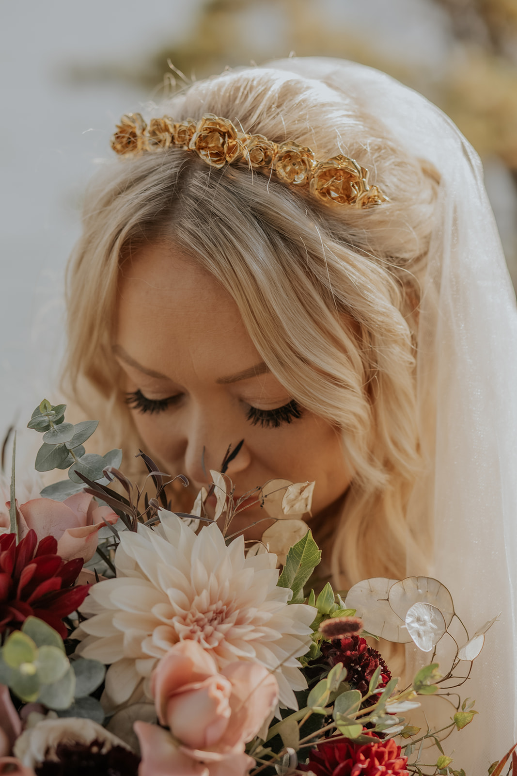 Bride smelling her pink and red bouquet.