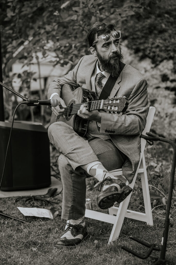 Man playing guitar at an outdoor wedding ceremony in Maine.