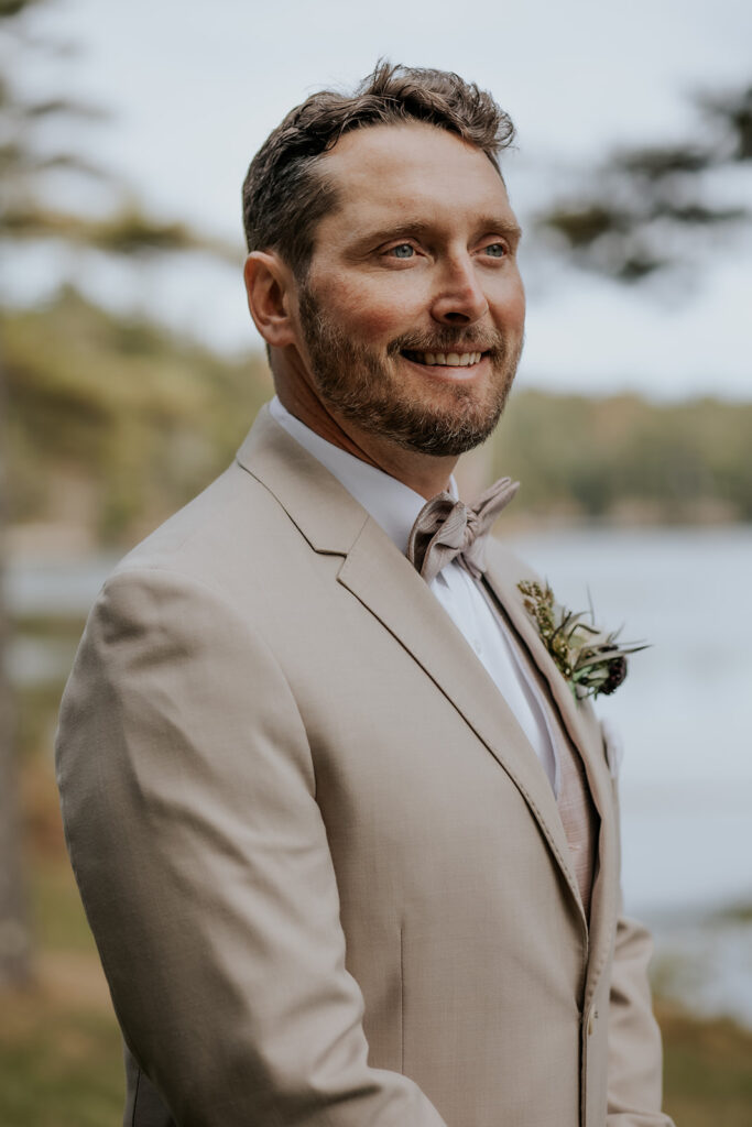 Groom in tan suit watching his bride walk down the aisle.