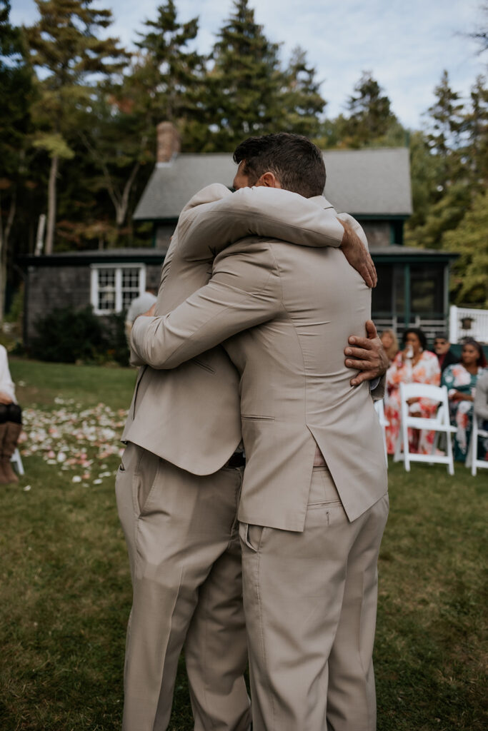 Groom and groomsmen hugging at the altar.