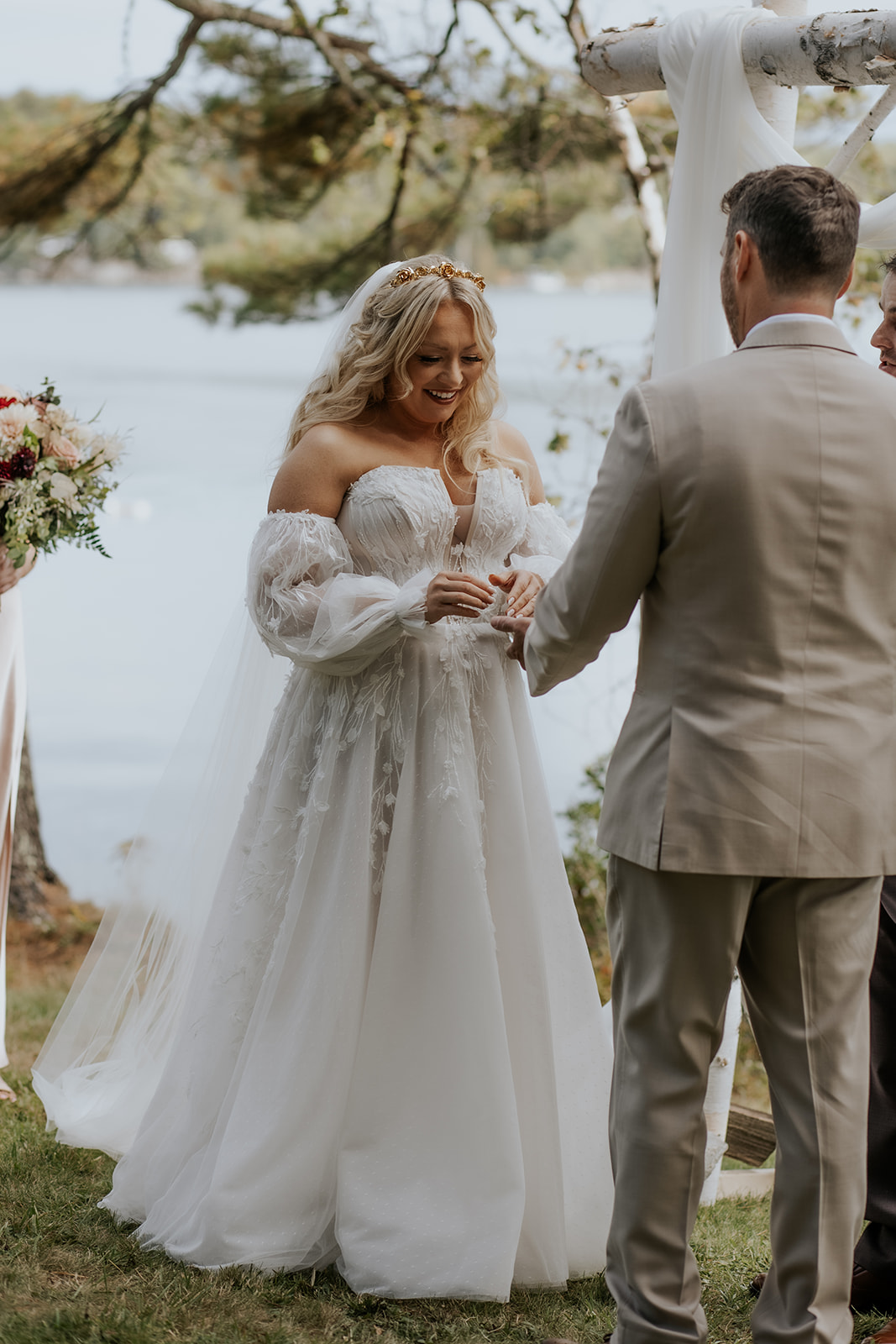 Bride putting on the groom's ring during outdoor ceremony in Maine.