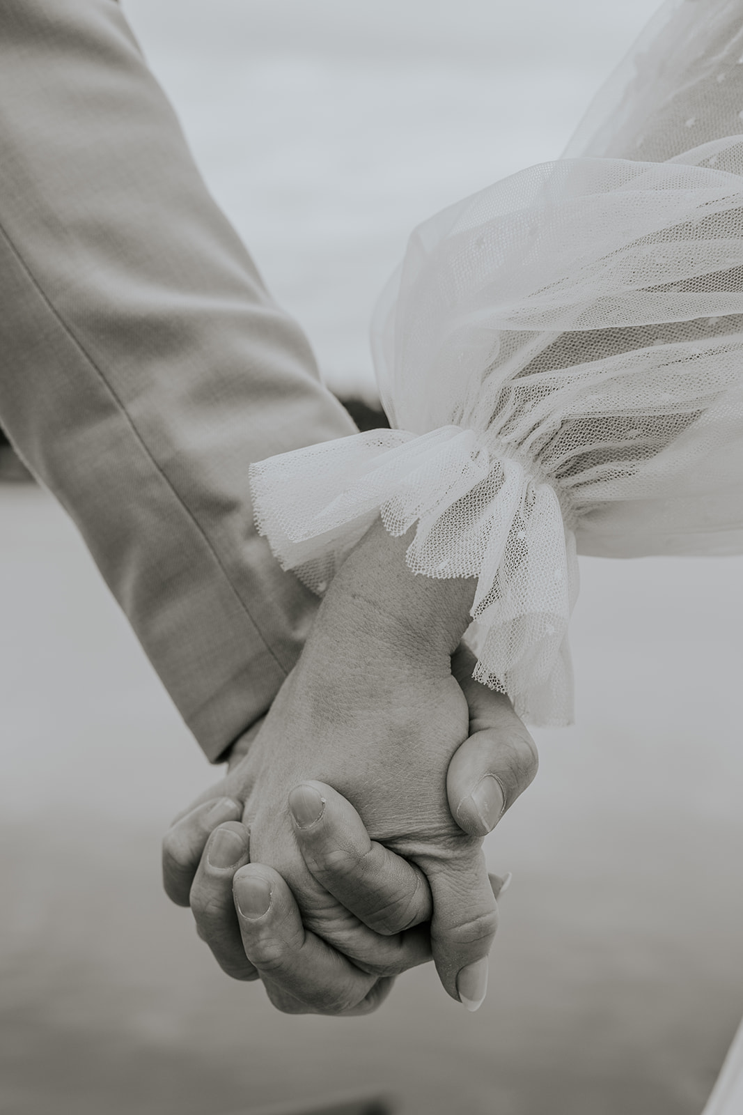 Bride and groom holding hands detail photo.
