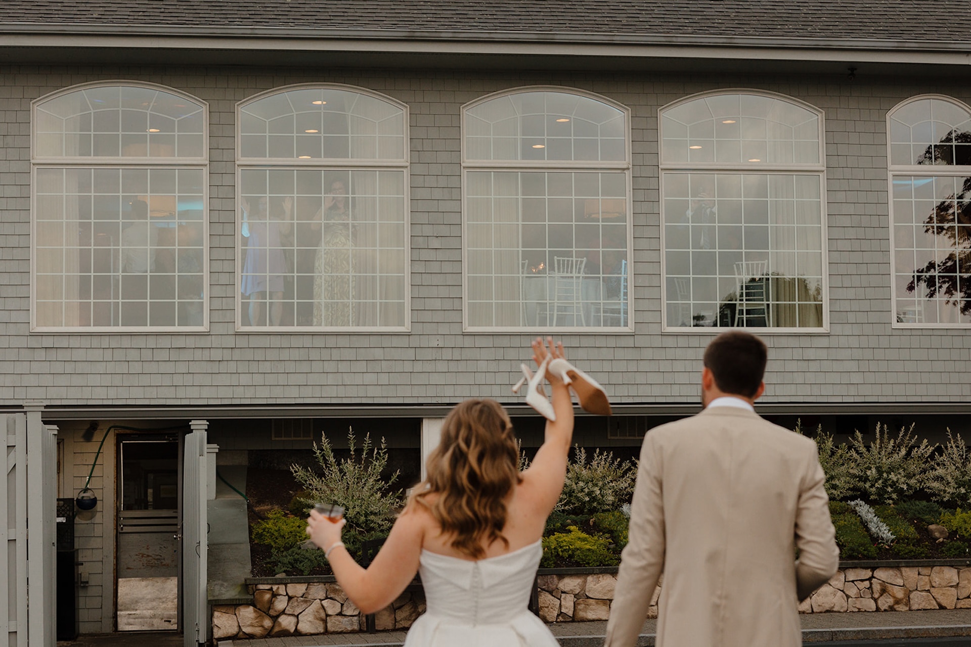 Bride holding her shoes in the air while walking with her groom toward the reception venue, highlighting candid post-ceremony joy and Destination Wedding Location Ideas.