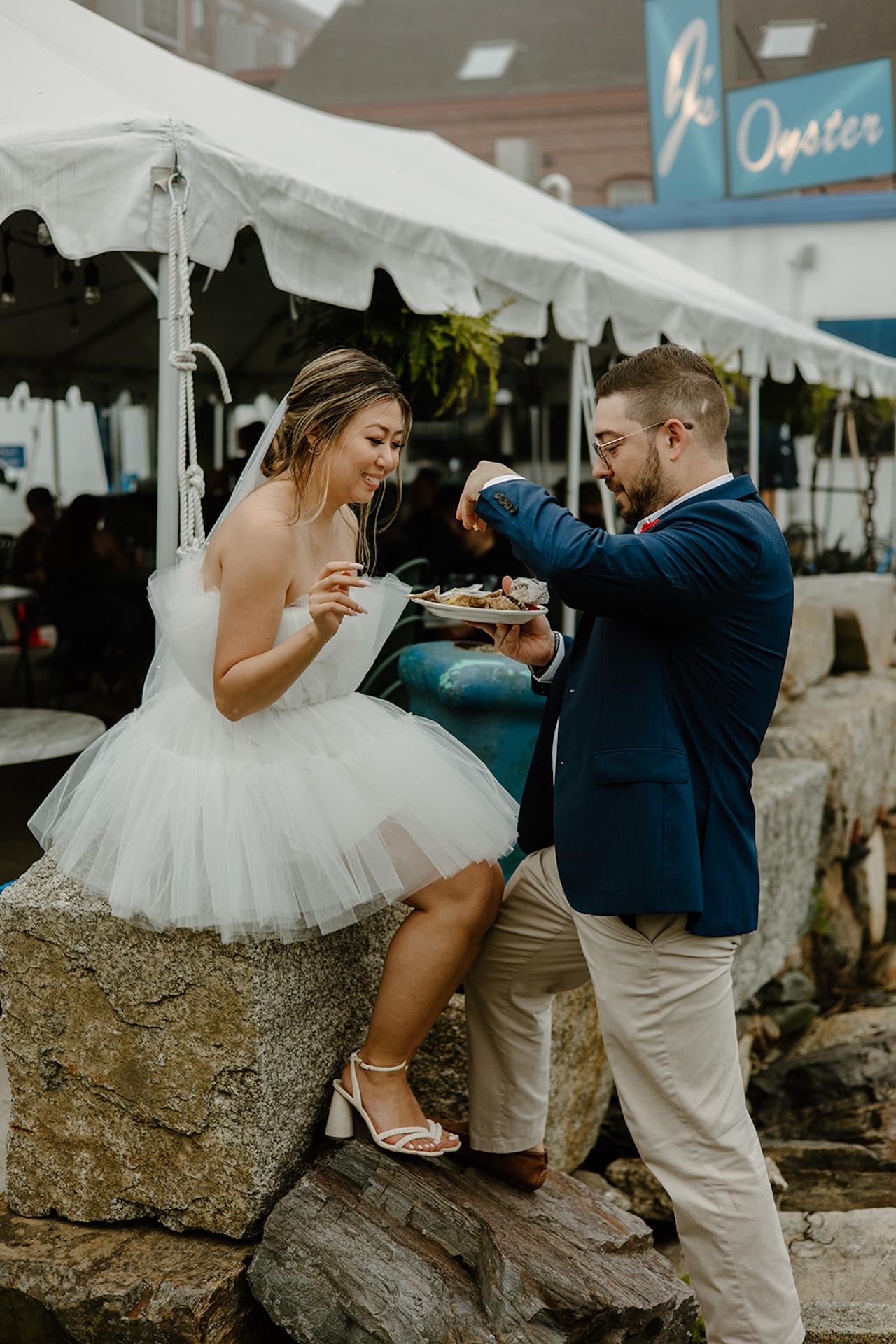 Bride and groom enjoying oysters outside a local restaurant, a playful moment that captures Destination Wedding Location Ideas in Portland, Maine.