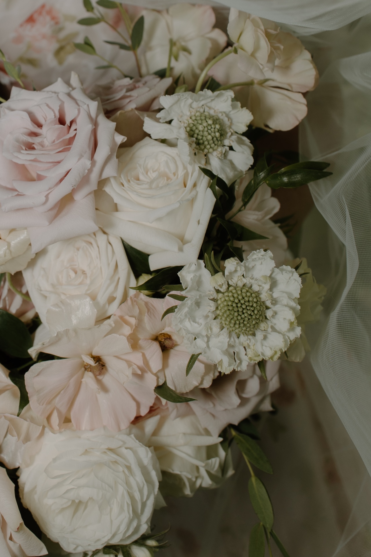 A close-up of the bridal bouquet with soft blush roses, white ranunculus, and greenery, captured at a Portland Maine wedding venue.