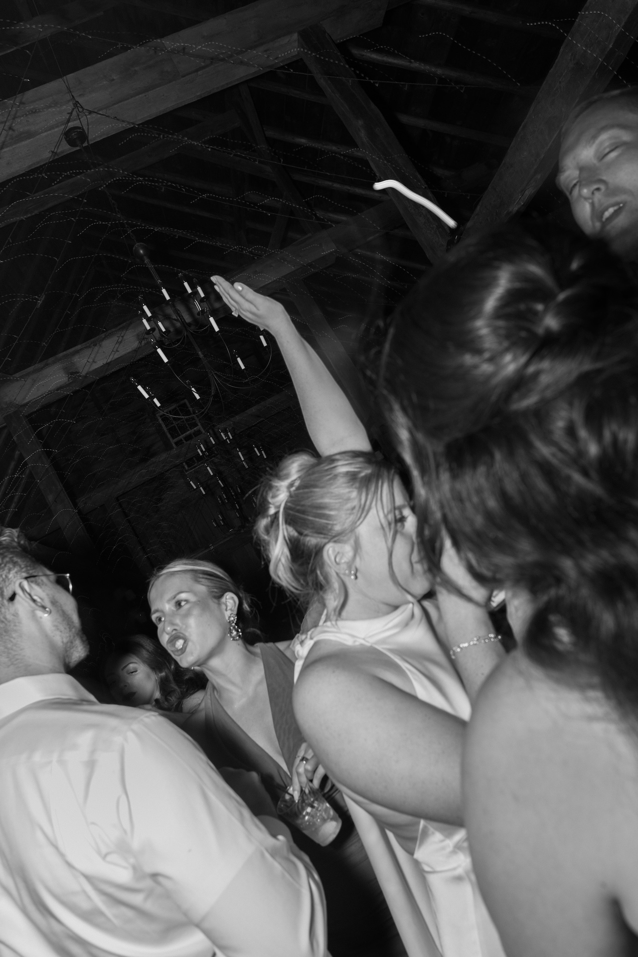 Guests dancing in the barn at night, captured in a candid black and white party photo.