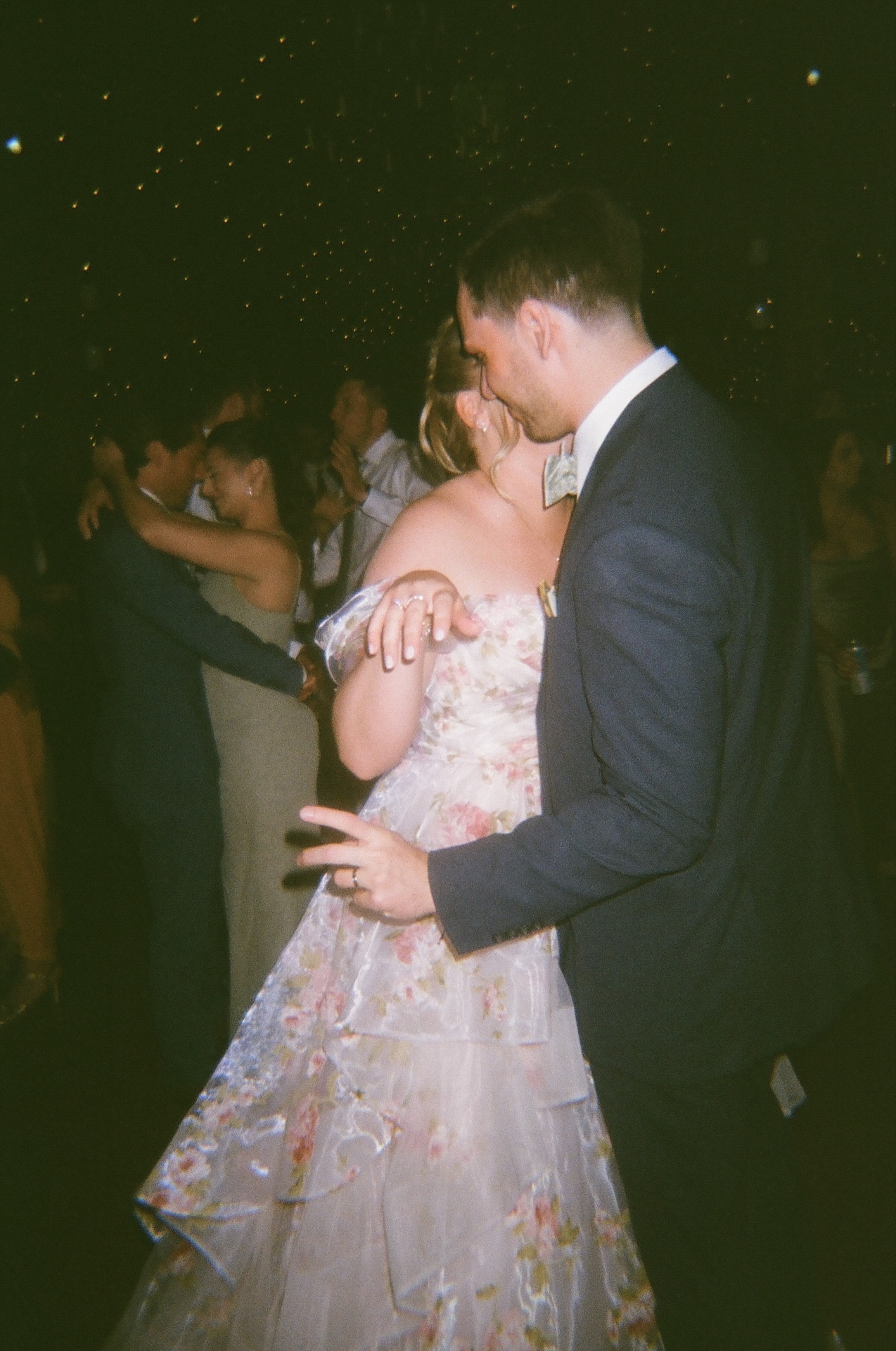A candid reception photo of the couple dancing closely under twinkling string lights at a Portland Maine wedding venue.