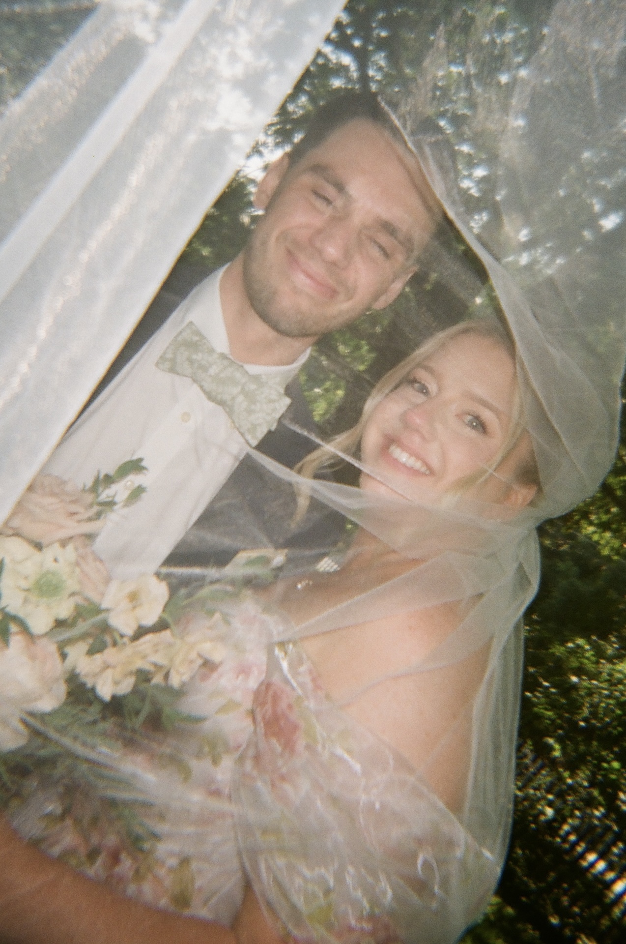 A playful veil shot of the bride and groom smiling together, framed by flowing tulle at a Portland Maine wedding venue.