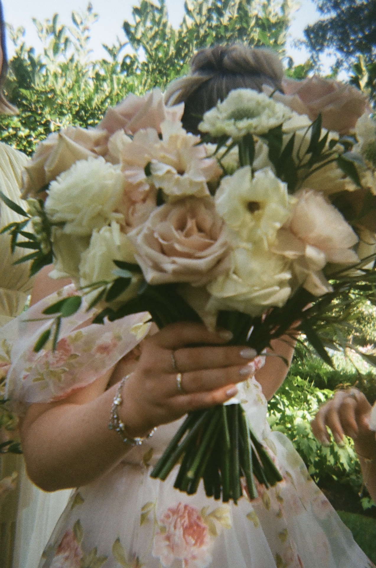 A close-up of the bridal bouquet filled with pale pink roses, cream blooms, and soft greenery.