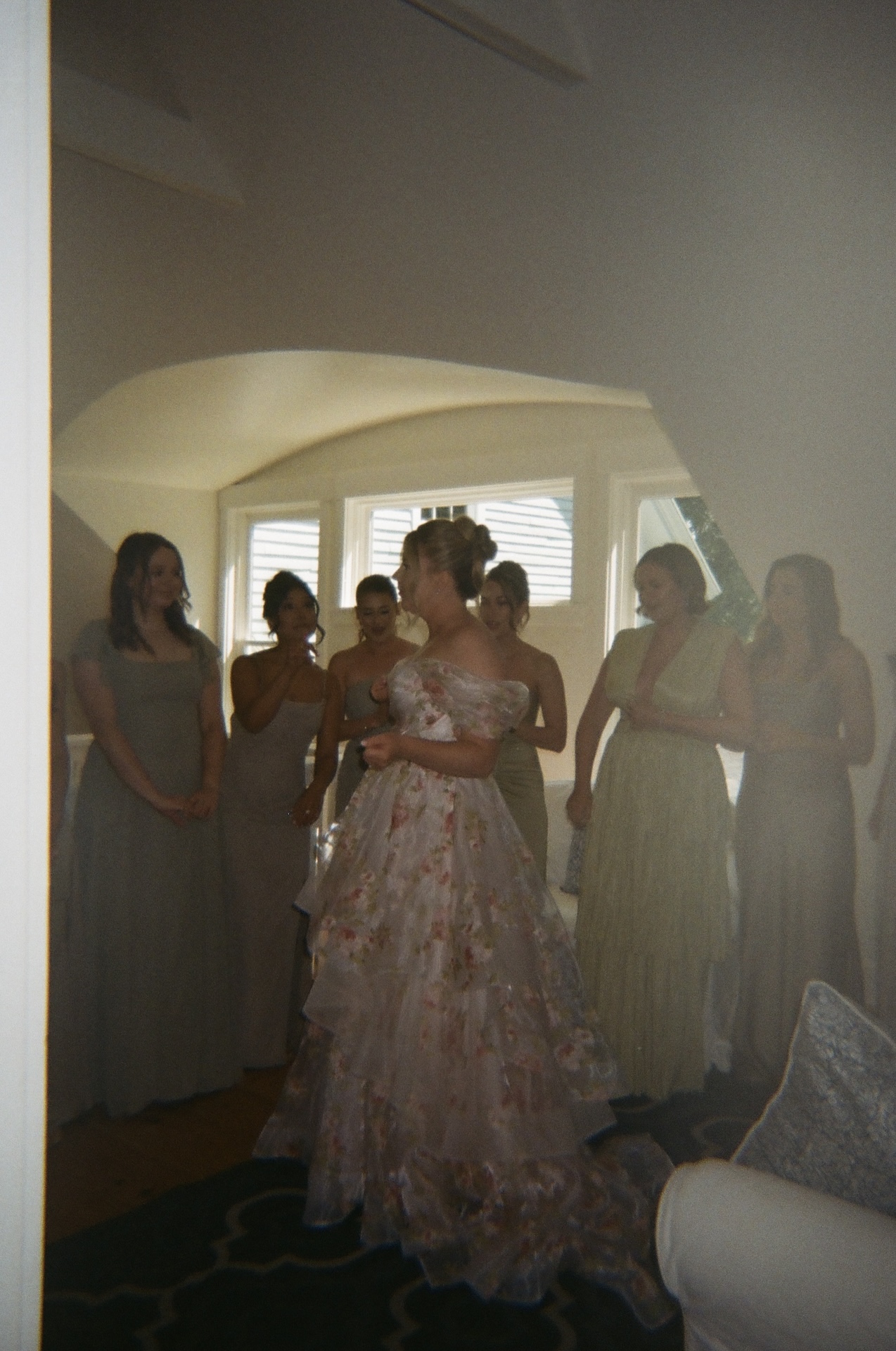 The bride standing with her bridesmaids inside the farmhouse, showing her floral gown during a quiet pre-ceremony moment at a Portland Maine wedding venue.