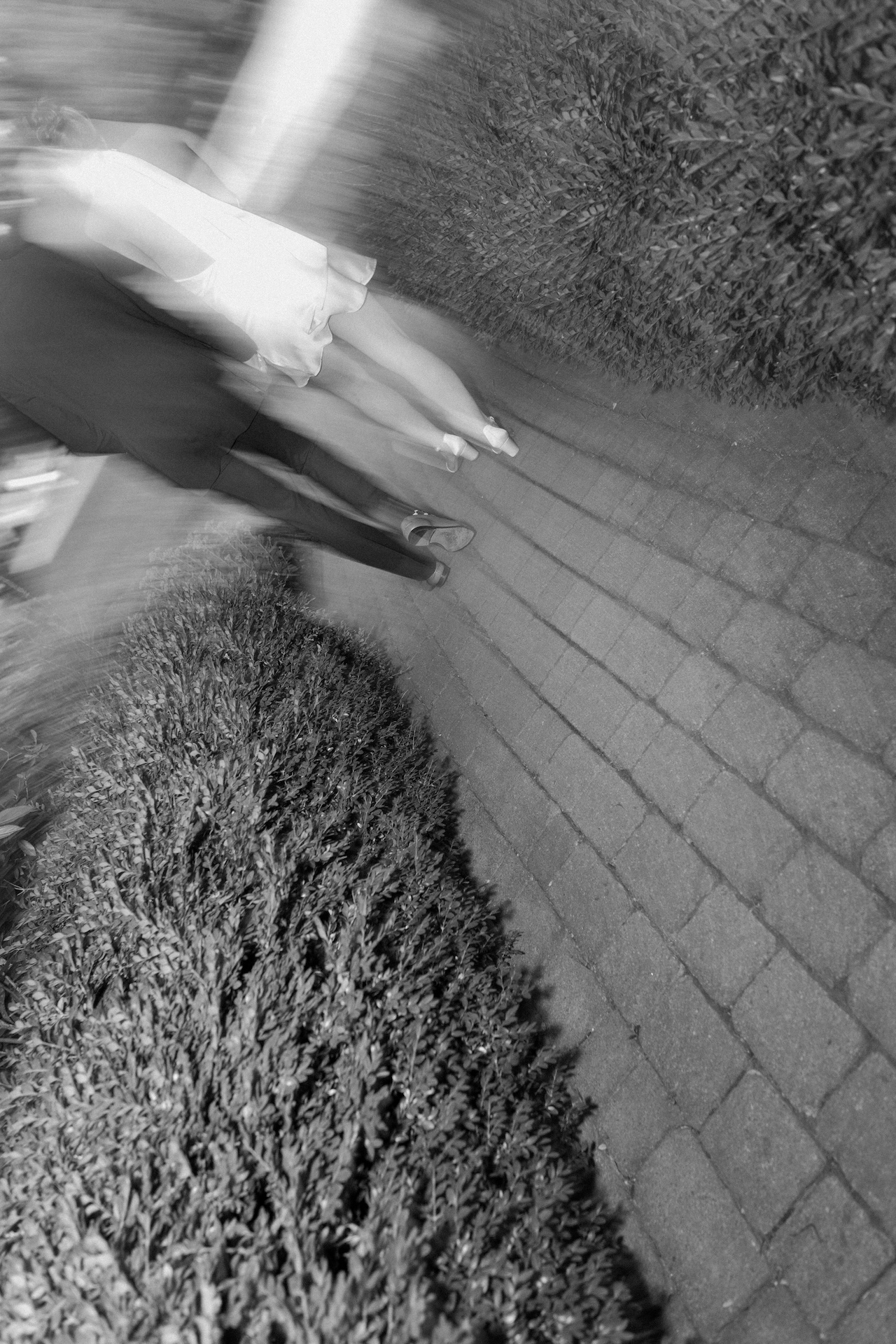 A motion-blur photo of the couple walking hand in hand down the cobblestone path in the evening.
