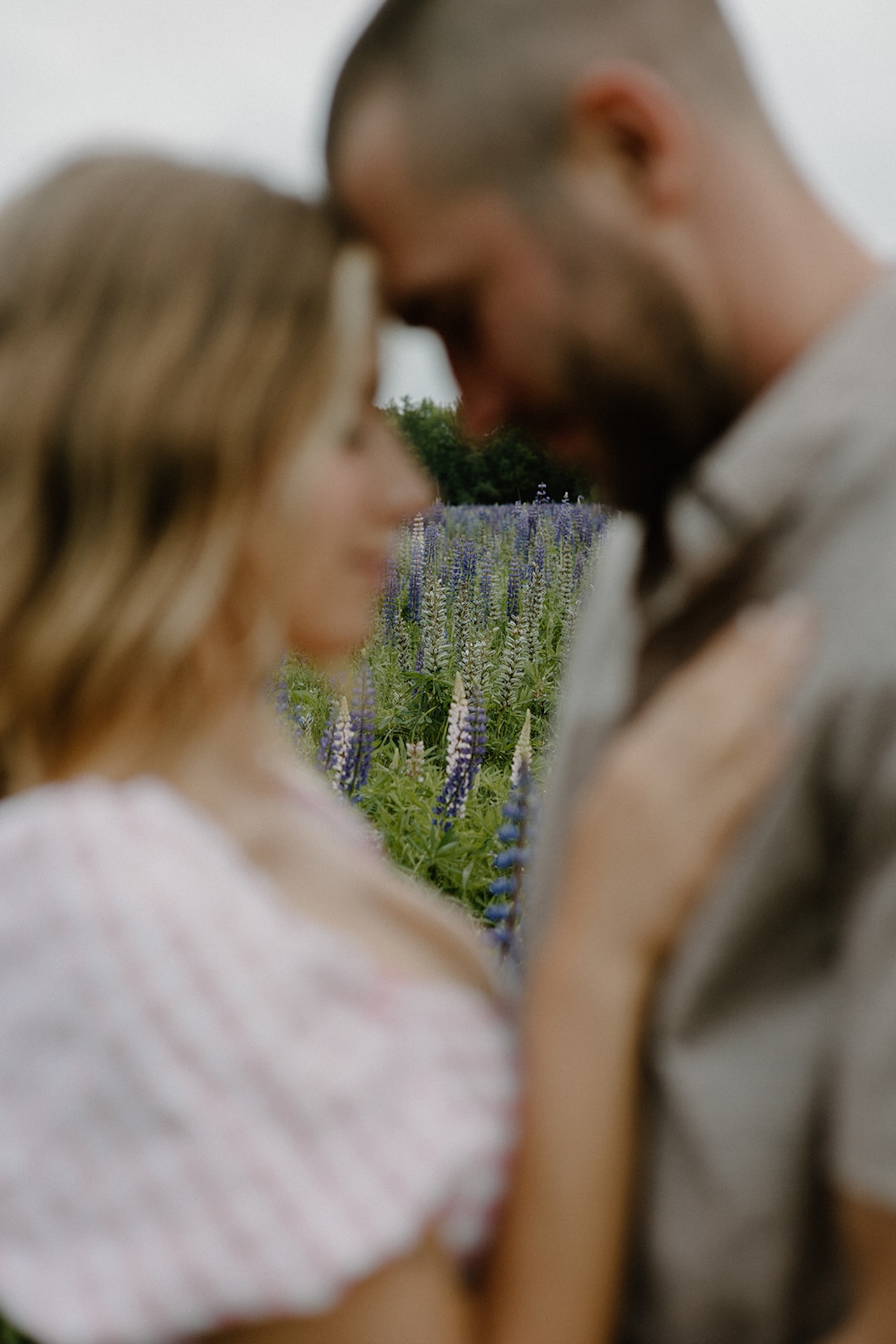 Softly blurred photo of a couple touching foreheads in a wildflower field, focusing on the dreamy emotion of the moment for spring engagement photo locations near Portland Maine.