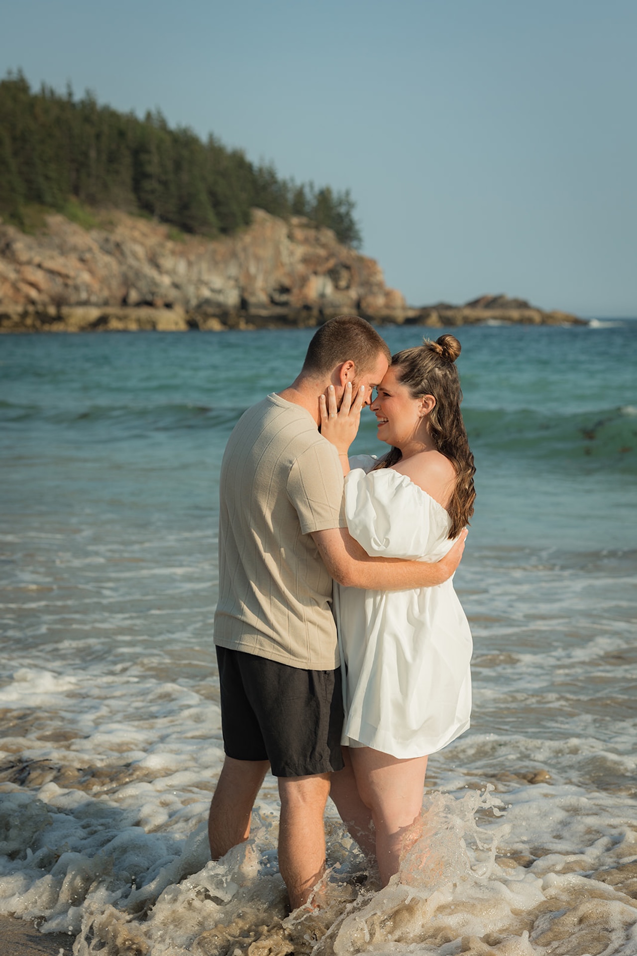 Couple touching foreheads and hugging with their feet in the water at Acadia National Park during their Acadia Engagement photos