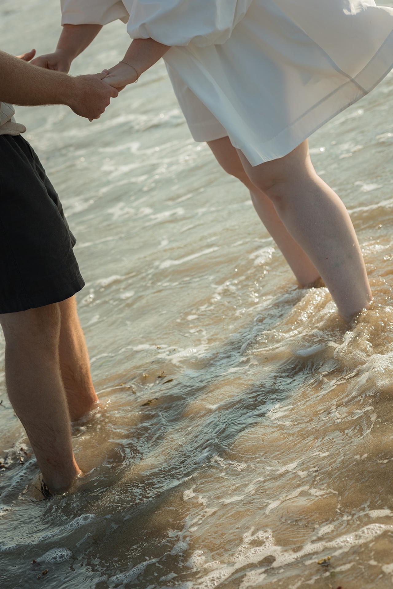 A detail shot of the couple playing in the water and holding hands at Acadia National Park