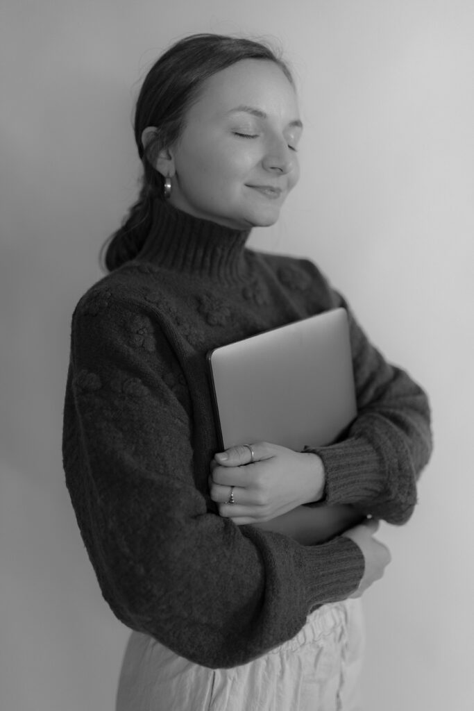Branding photo for a photographer of her holding her laptop and smiling softly for a blog about her favorite CRM for businesses