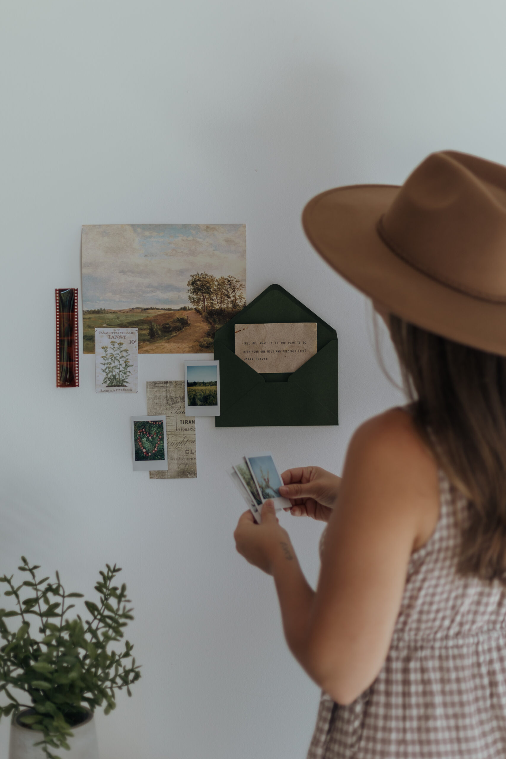 Brand photos for a photographer: She is placing a flatlay of polaroids on a wall for a unique twist on her branding photoshoot.