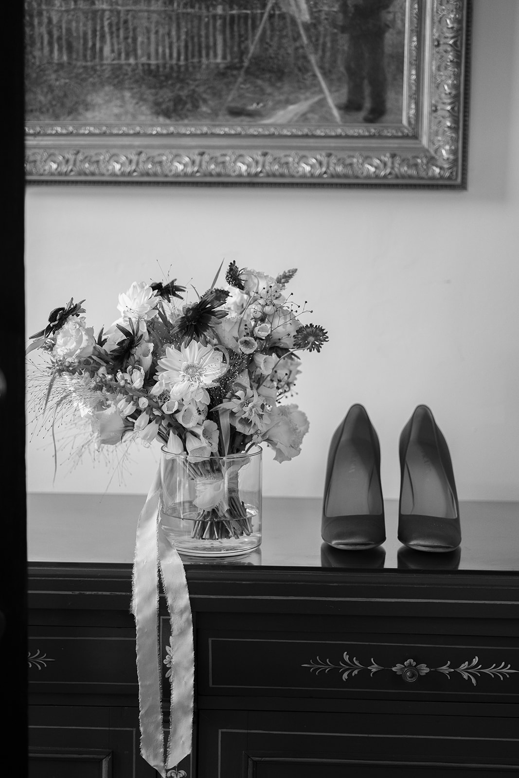 Black and white photo of bridal bouquet and shoes on wedding day. 