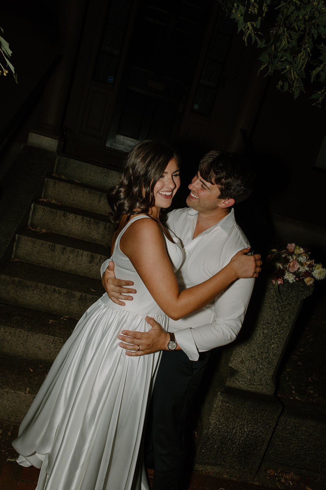 The couple sitting together on the stone steps, the groom holding the bride close.