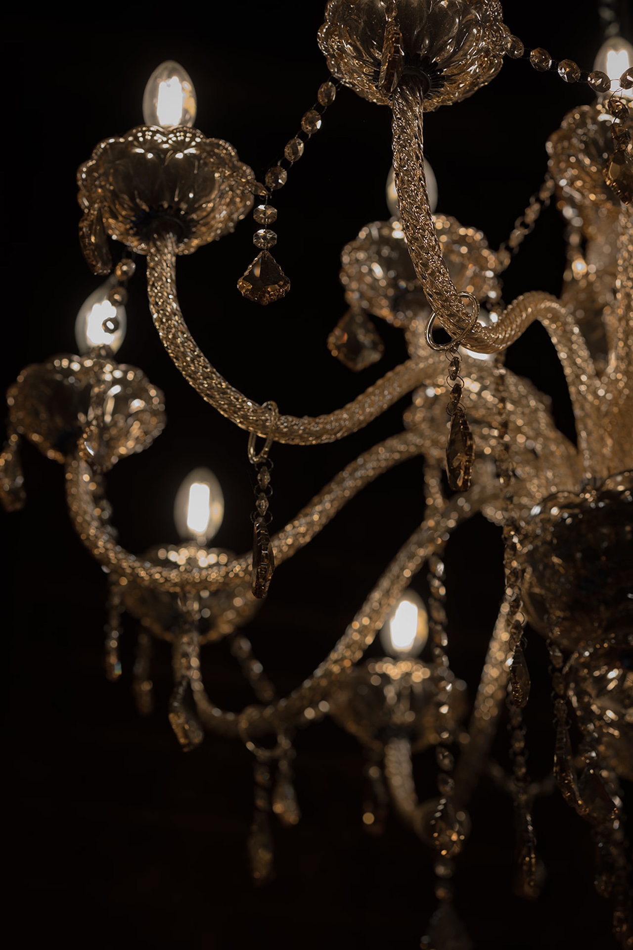 Close-up of an ornate crystal chandelier glowing warmly in the reception space.