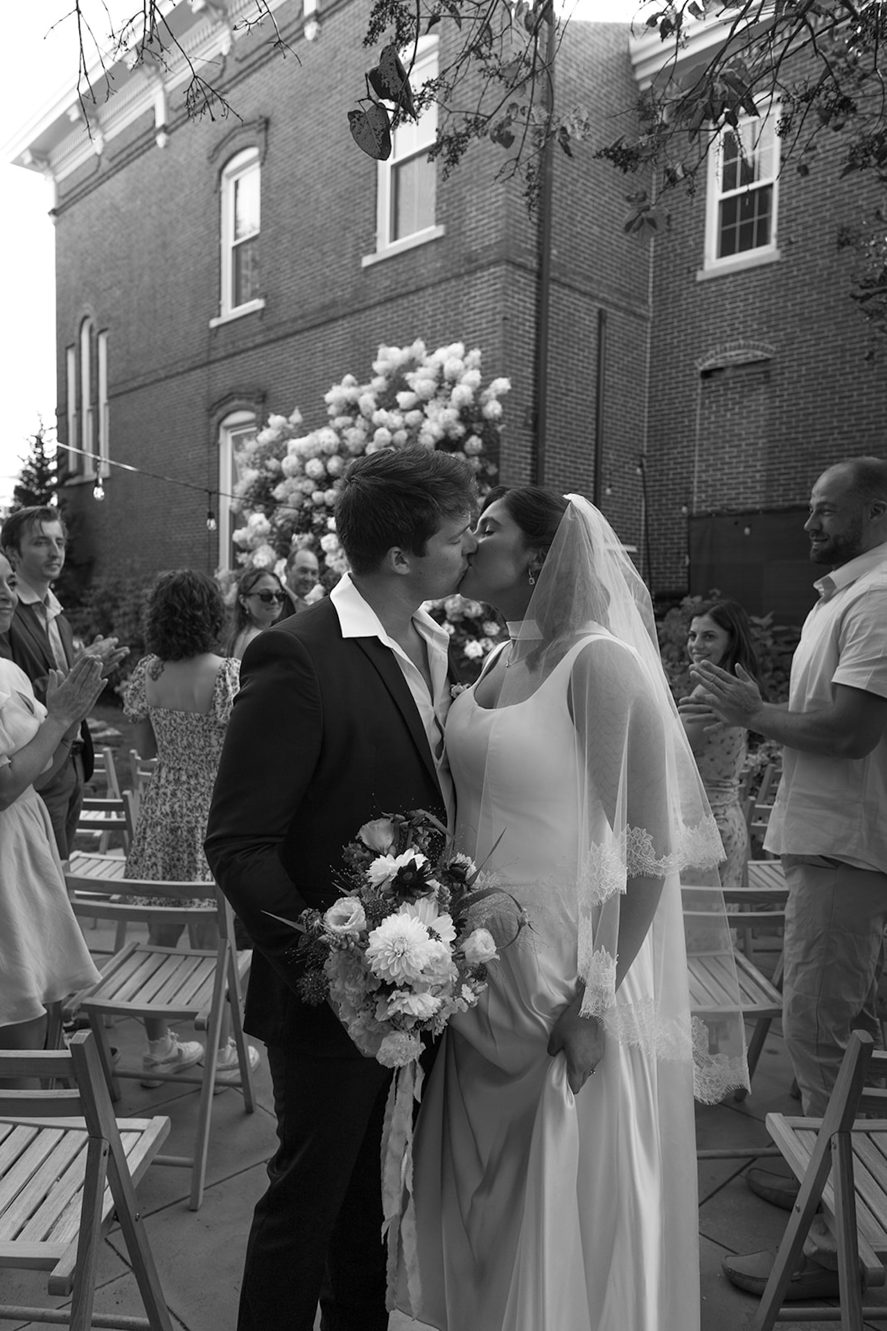 The couple shares a sweet kiss at the end of their ceremony while guests clap around them.
A timeless moment framed by blooming hydrangeas at a classic Historic Wedding Venue.