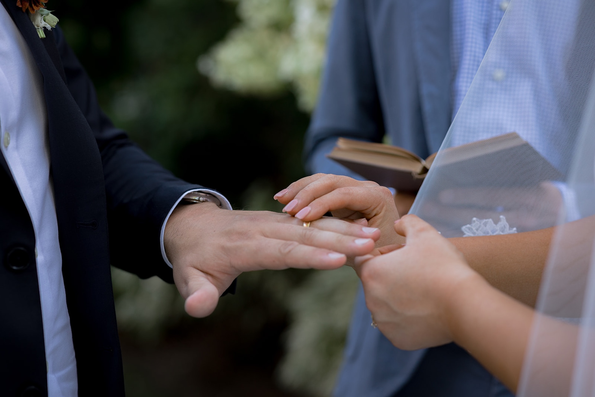 A close-up of the bride placing the ring on the groom’s hand during their vows.

