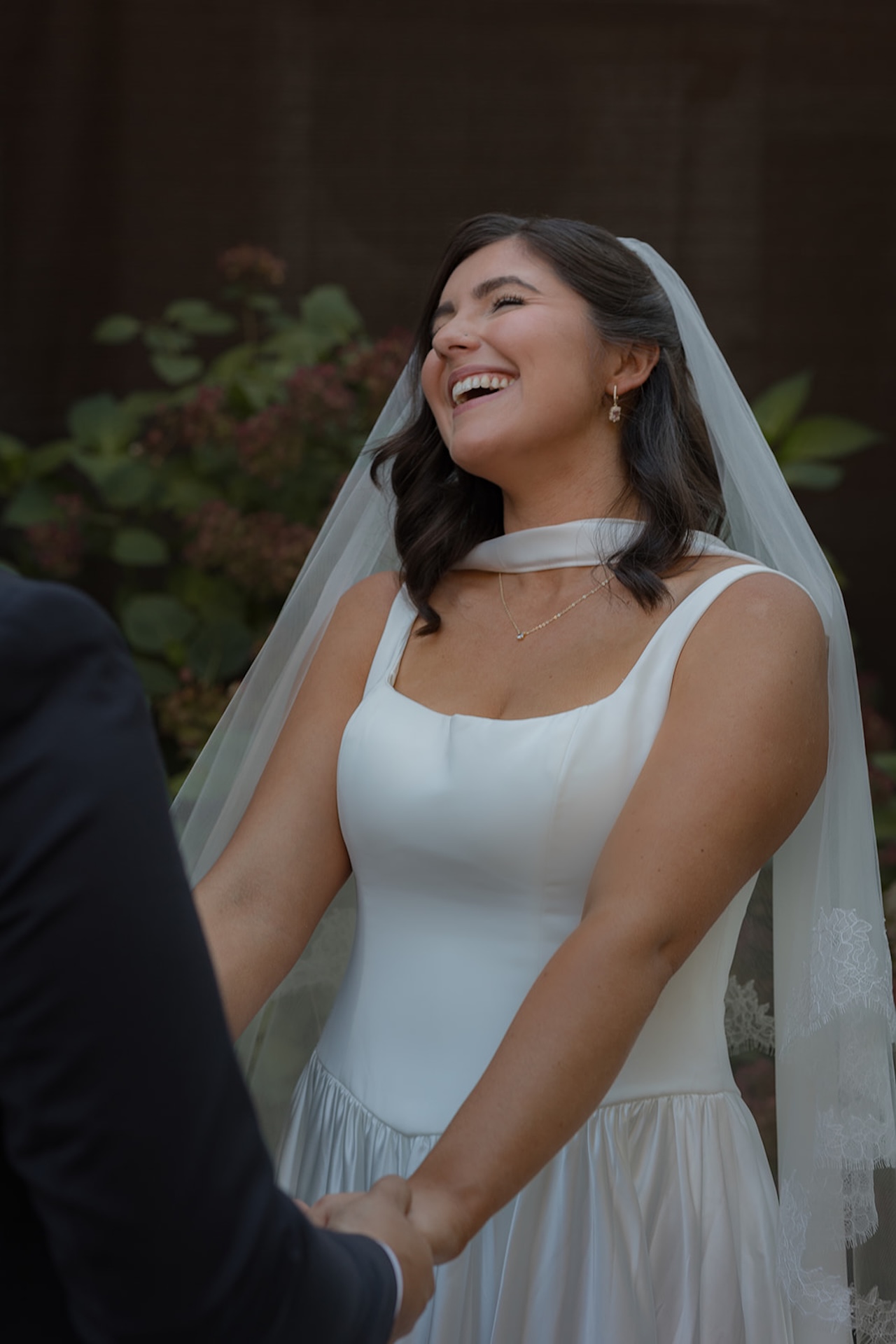 The bride laughs mid-ceremony, holding her partner’s hands as the moment sinks in.

