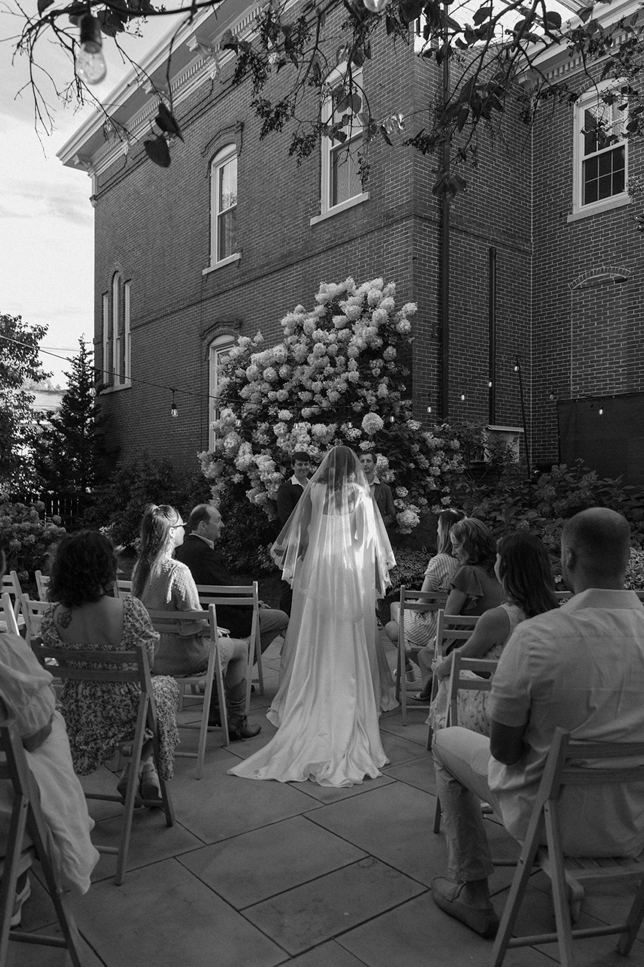 The bride walks toward the ceremony with her veil glowing in the afternoon light.

