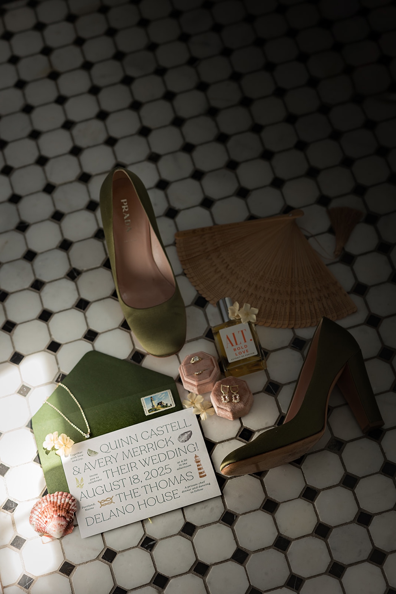 Flatlay of the bride’s details — olive green Prada heels, jewelry, invitations, florals, and perfume arranged on vintage tile inside a Historic Wedding Venue.
